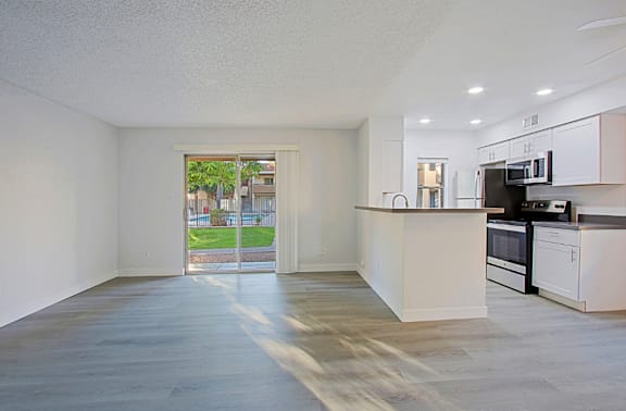 A spacious kitchen with white cabinets and a view of a backyard through a glass door.