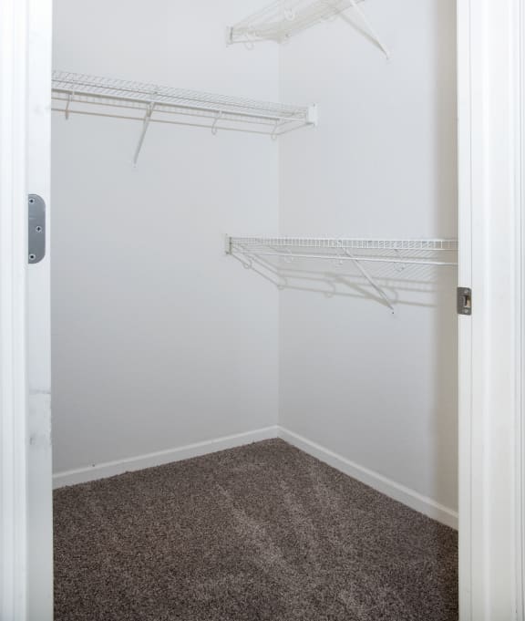 an empty closet with white shelves and white walls and carpet