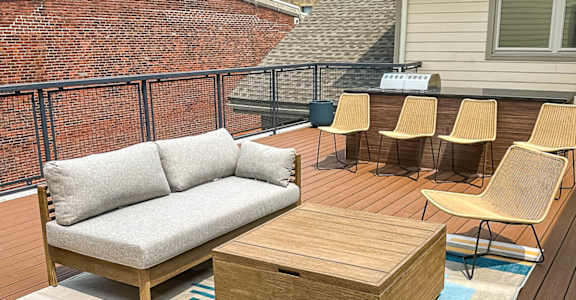 a furnished patio with a couch and tables on a roof