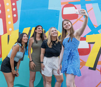 a group of girls taking a picture in front of a graffiti wall