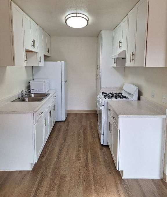 an empty kitchen with white cabinets and white appliances