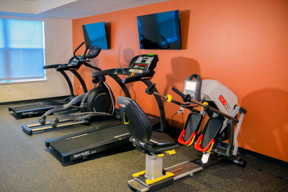 a gym with two exercise bikes and two televisions
