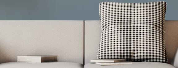 a white chair with a black and white checkered pillow in a living room