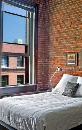 a bedroom with a bed and a brick wall