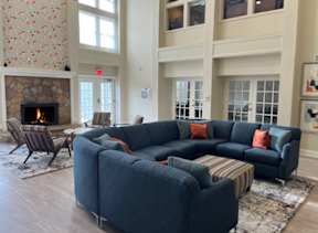 A living room with a fireplace and a grey couch.