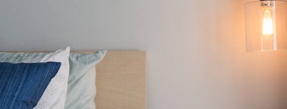 A bed with a white comforter and a lamp on a side table.