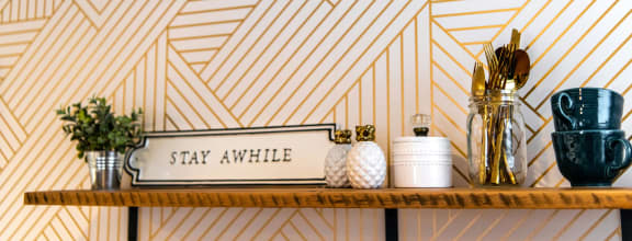 a shelf in a bathroom with a geometric wallpaper