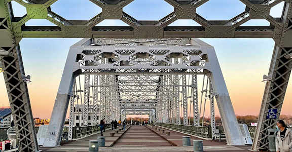 A man is standing on a bridge with a metal structure.