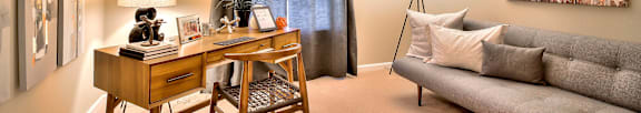 A room with a desk, couch, and pictures on the wall.