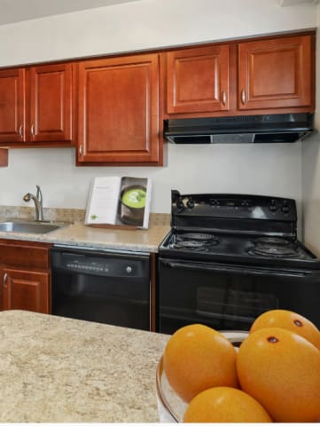 a kitchen with black appliances and brown cabinets  at Donnybrook Apartments, Towson MD