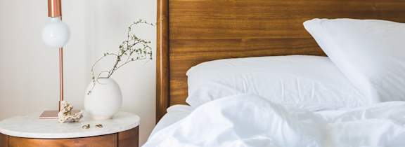 A bed with white pillows and a wooden headboard.
