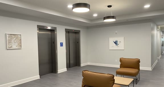 a waiting room in a hospital with three chairs and two elevators