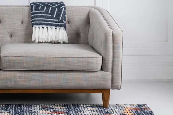 A grey couch with a striped throw blanket on it.