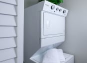 Thumbnail 11 of 23 - Mandarin Bay apartments in Jacksonville, FL in-unit laundry. Machine is a stacked whirlpool washer and dryer in a closet with shuttered door
