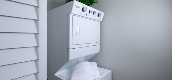 Mandarin Bay apartments in Jacksonville, FL in-unit laundry. Machine is a stacked whirlpool washer and dryer in a closet with shuttered door