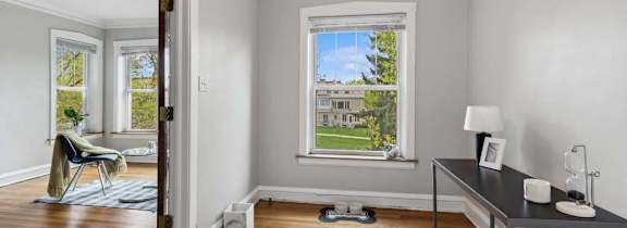 A room with a wooden floor and a window overlooking a green lawn.