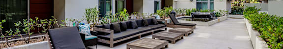a row of lounge chairs in a courtyard between two apartment buildings