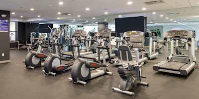 A gym with a variety of exercise equipment including treadmills, stationary bikes, and weight machines.