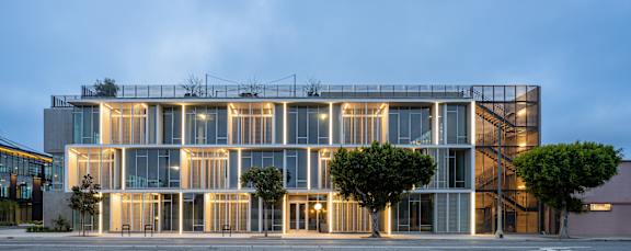 A modern building with a glass facade and a tree in front of it.