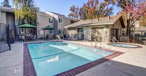 A swimming pool surrounded by a fence and a gazebo in the background.