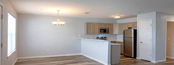 an empty living room and kitchen with a refrigerator and a sink