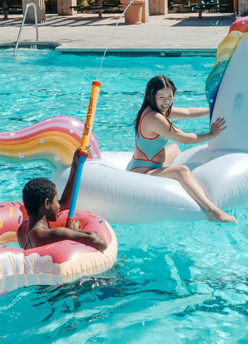 a group of people in a pool with inflatable toys and a unicorn float