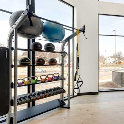 A gym with a row of exercise bikes and a rack of kettlebells.