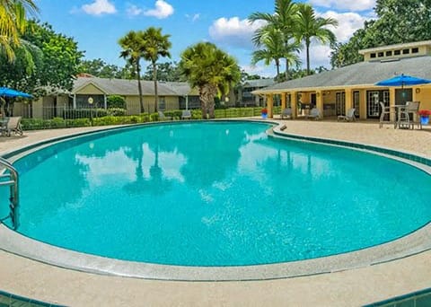 Large swimming pool with a building in the background at Aqua Bay Apartments in Naples, FL 34116
