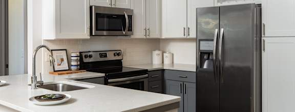 A kitchen with a white counter top and a black refrigerator.