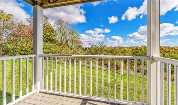 a balcony with a view of the grass and trees