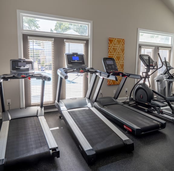 a gym with treadmills and other exercise equipment at the enclave at woodbridge apartments in