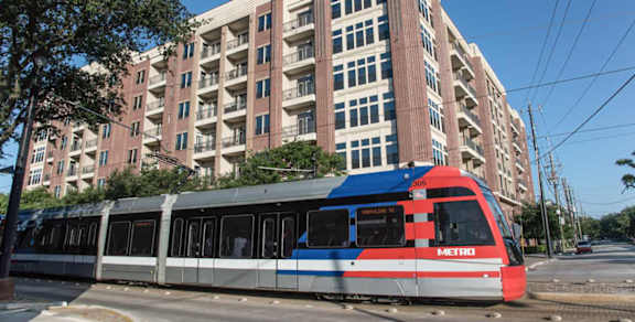 a train on the street in front of a tall building