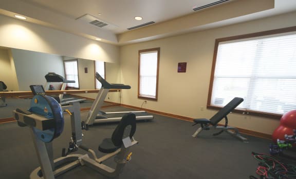 a workout room with a simulator and exercise equipment at Senior Living at Cambridge Heights