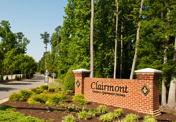 Community entrance with brick sign; road surrounded by trees