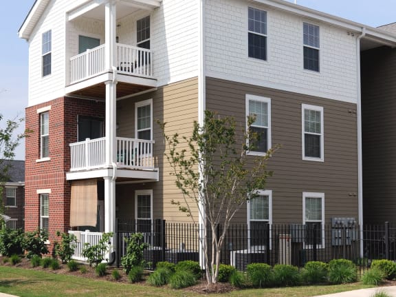 a white and brown apartment building with a sidewalk