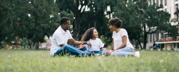 a family sitting in the grass on a sunny day