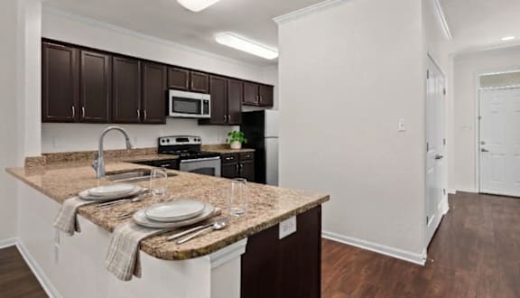 A kitchen with brown cabinets and a granite countertop.
