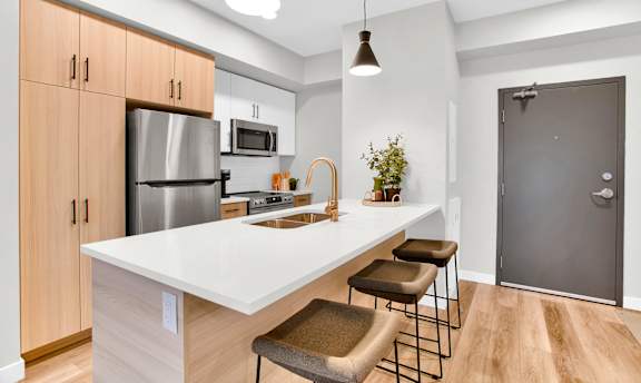 A kitchen with a white countertop and wooden cabinets.