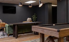 A pool table with a green cloth and a television on the wall.