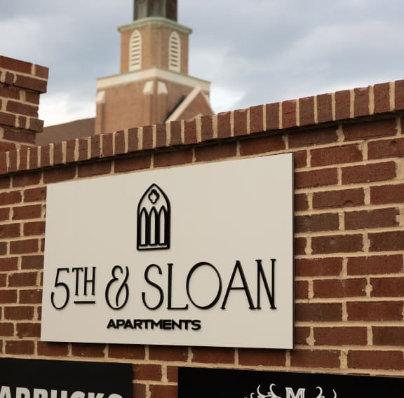 the sign for 5th  sloan apartments in front of a church steeple