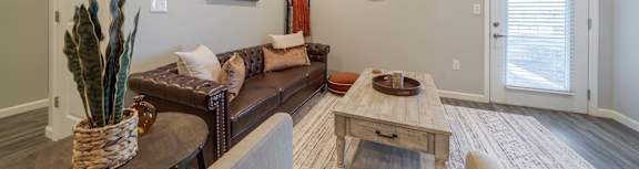 A modern living room with a white chair, a grey couch, and a wooden wall.