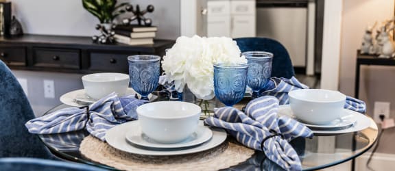 a dining room table with blue chairs and a glass table top
