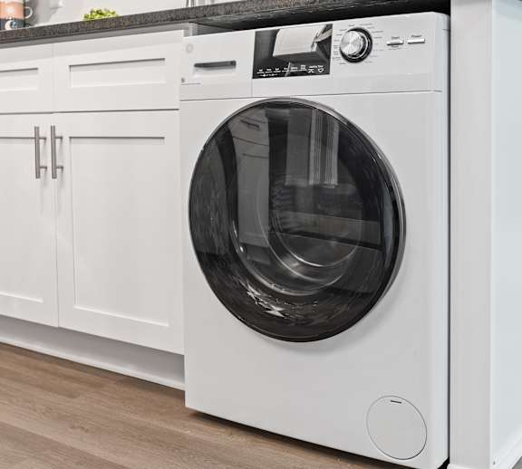A white front loading washing machine in a kitchen.
