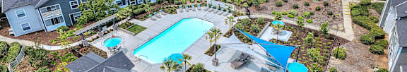A large swimming pool surrounded by a landscaped garden and apartment buildings.