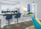 Thumbnail 4 of 23 - View of kitchen in Mandarin bay apartment in Jacksonville from living room. Kitchen has a two-seater island dinette with modern bar height stools.