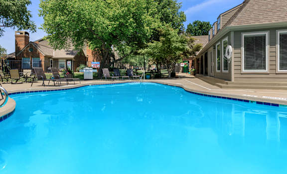 A blue pool with tree and building behind it