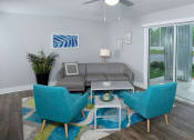 Thumbnail 7 of 23 - Living room in Mandarin Bay apartments in Jacksonville, FL with midcentury modern grey and blue seating, ceiling fan, and blue, green, and grey rug.