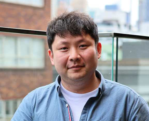 A man in a blue shirt stands on a balcony.