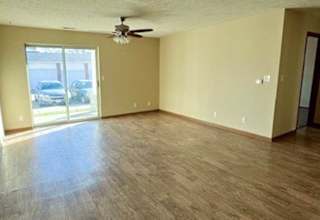 a living room with hardwood flooring and a ceiling fan