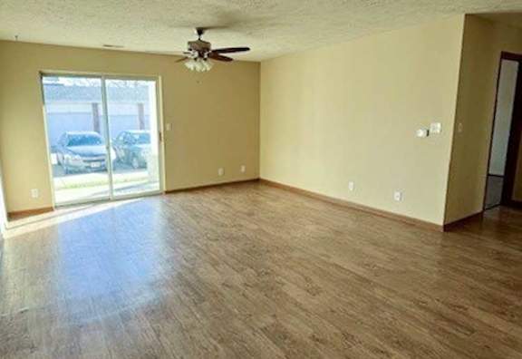 a living room with hardwood flooring and a ceiling fan